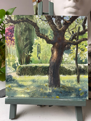 Close view of the garden tree, green foliage and hanging wind chime in Beneath the Old Tree.